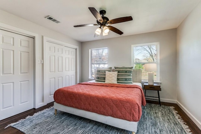 bedroom featuring visible vents, a closet, dark wood-style flooring, baseboards, and ceiling fan