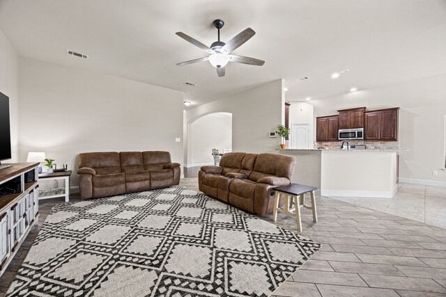 living area with arched walkways, ceiling fan, recessed lighting, and visible vents