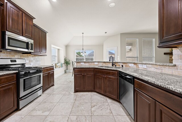 kitchen featuring dark brown cabinetry, light stone countertops, tasteful backsplash, a sink, and appliances with stainless steel finishes