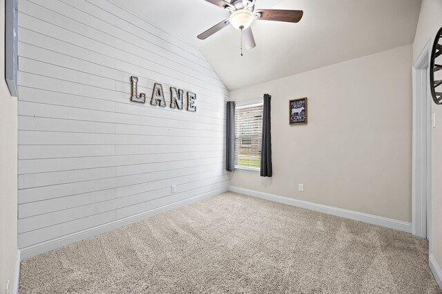 carpeted empty room with wooden walls, baseboards, ceiling fan, and lofted ceiling