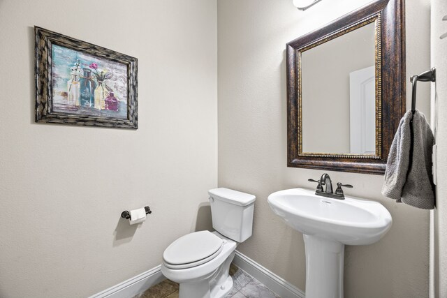 bathroom with toilet, baseboards, and tile patterned floors