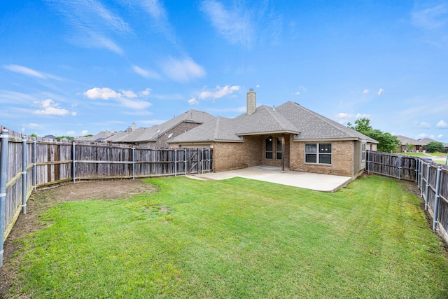 rear view of house with a fenced backyard, a chimney, brick siding, a patio area, and a lawn