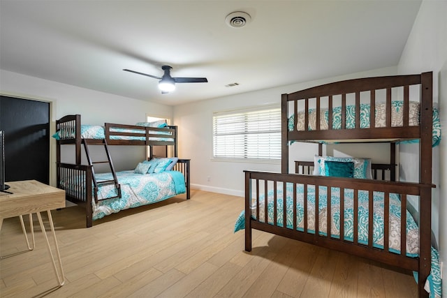bedroom featuring baseboards, ceiling fan, wood finished floors, and visible vents