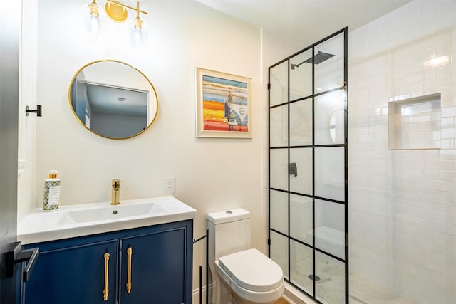 bathroom featuring vanity, a tile shower, and toilet