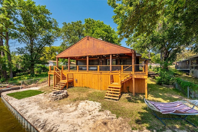 rear view of property with a wooden deck, fence, stairs, and a fire pit