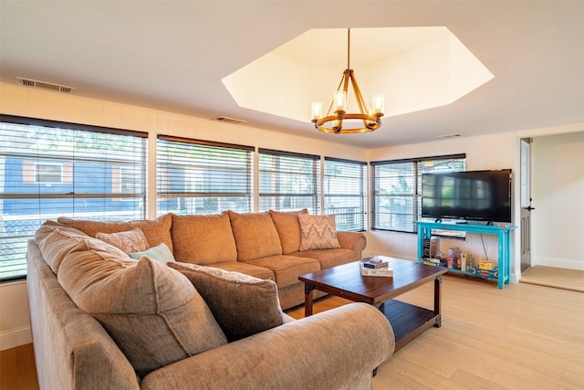 living area with baseboards, a notable chandelier, visible vents, and light wood-type flooring