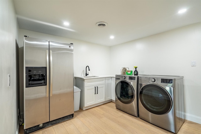 washroom featuring laundry area, a sink, light wood finished floors, visible vents, and washing machine and dryer