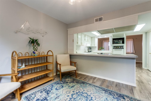kitchen with light wood-style floors, visible vents, built in microwave, and oven