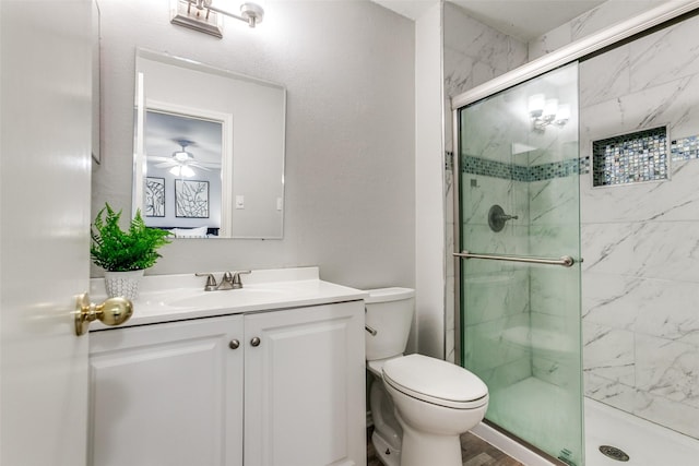 bathroom featuring vanity, ceiling fan, a stall shower, and toilet
