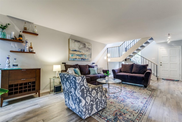 entrance foyer featuring stairway, baseboards, rail lighting, and wood finished floors