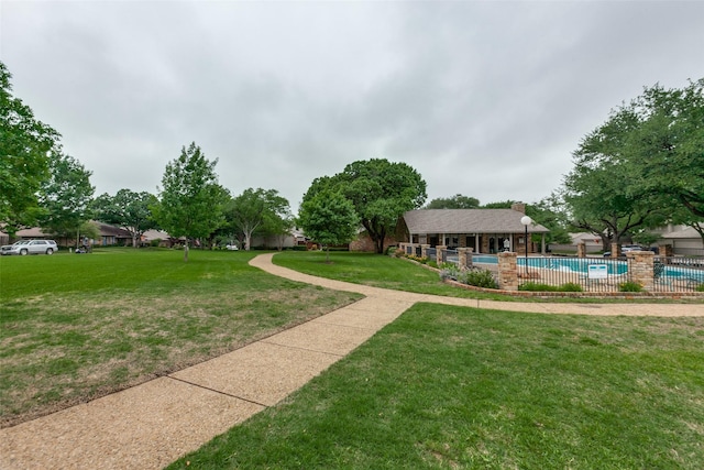 view of property's community featuring fence, a yard, and a pool