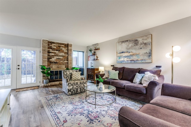 living room featuring french doors, a brick fireplace, and wood finished floors