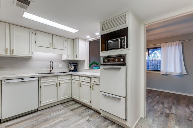 kitchen featuring white cabinets, a sink, white appliances, light countertops, and visible vents