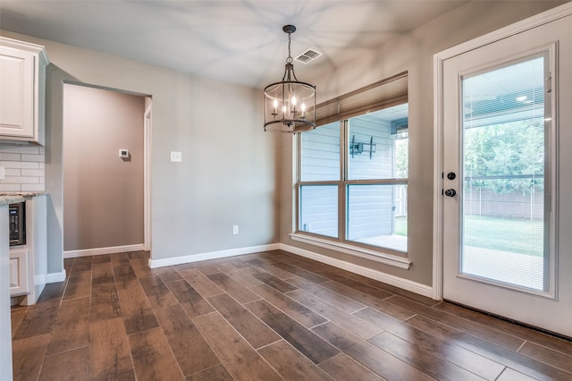 unfurnished dining area featuring visible vents, baseboards, a chandelier, and dark wood-style floors