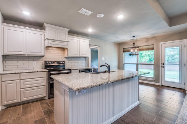 kitchen with visible vents, wood finish floors, white cabinets, range with two ovens, and a sink