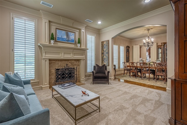 carpeted living room with crown molding, arched walkways, a notable chandelier, and visible vents