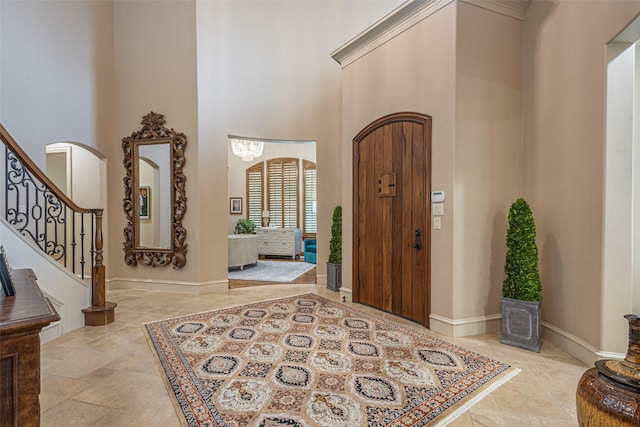 foyer featuring a high ceiling, arched walkways, baseboards, stone finish flooring, and stairway