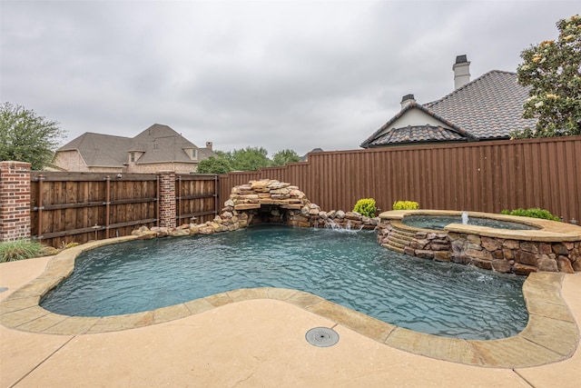 view of pool with a fenced backyard and a pool with connected hot tub