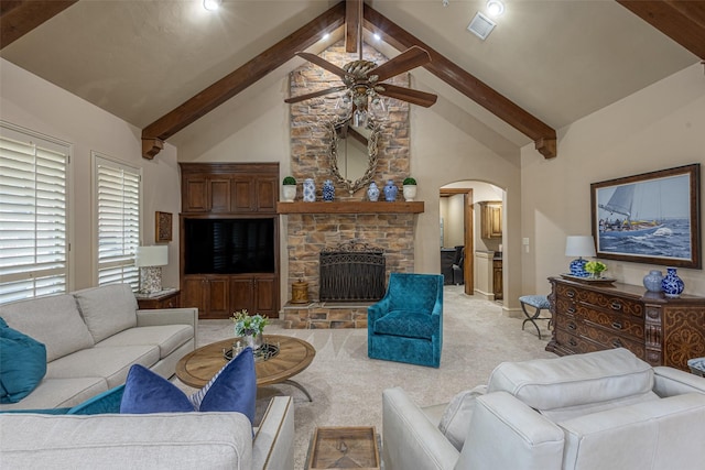 living area featuring arched walkways, a ceiling fan, light carpet, and beamed ceiling