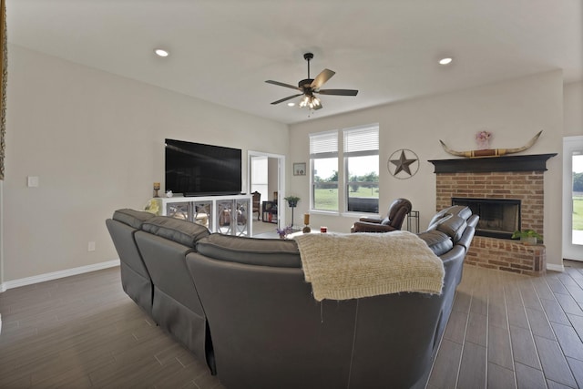 living room featuring dark wood-type flooring, a ceiling fan, a healthy amount of sunlight, and a fireplace