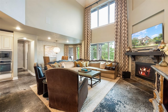 1005 Mallard Lakes Dr, Mckinney, TX 75072 - living area with a high ceiling, arched walkways, a fireplace, and baseboards