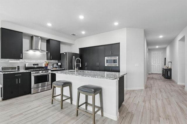 1036 Fairfax Dr, Godley, TX 76044 - kitchen with wall chimney range hood, appliances with stainless steel finishes, dark cabinetry, light wood-type flooring, and recessed lighting