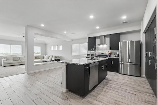 1036 Fairfax Dr, Godley, TX 76044 - kitchen with stainless steel appliances, wall chimney range hood, a sink, open floor plan, and dark cabinetry