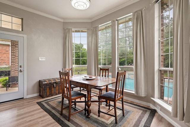 dining area featuring crown molding, baseboards, and light wood-style flooring