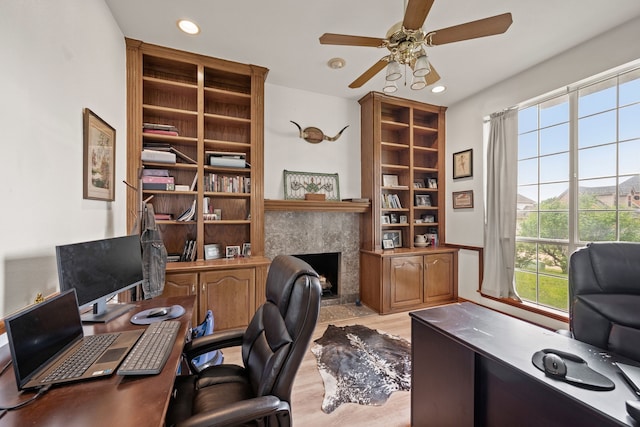 office space featuring built in features, a fireplace, ceiling fan, recessed lighting, and light wood-type flooring