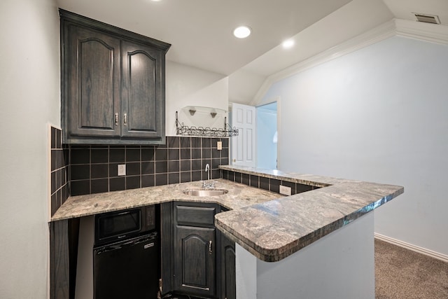 kitchen with visible vents, a peninsula, lofted ceiling, tasteful backsplash, and a sink