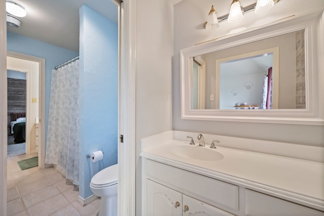 bathroom featuring vanity, baseboards, tile patterned floors, and toilet