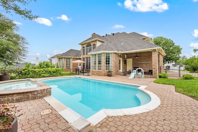 view of swimming pool featuring fence, a sunroom, a patio, and a pool with connected hot tub