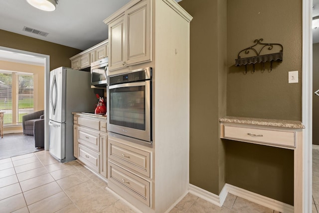 kitchen with visible vents, light countertops, cream cabinetry, light tile patterned floors, and stainless steel appliances