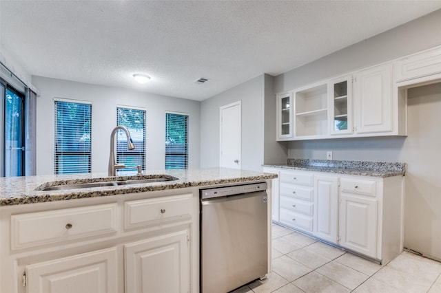 kitchen featuring dishwasher, a sink, light stone countertops, glass insert cabinets, and a textured ceiling
