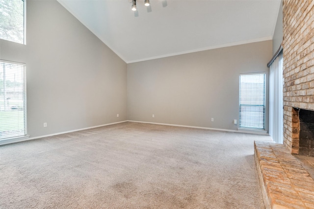 unfurnished living room with carpet flooring, a brick fireplace, ornamental molding, baseboards, and high vaulted ceiling