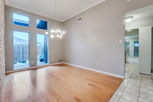 unfurnished dining area featuring a chandelier, baseboards, and a high ceiling