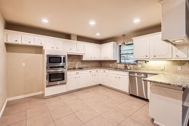 kitchen with appliances with stainless steel finishes, tasteful backsplash, a sink, recessed lighting, and white cabinetry