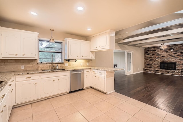 kitchen with a brick fireplace, a peninsula, open floor plan, white cabinetry, and stainless steel dishwasher