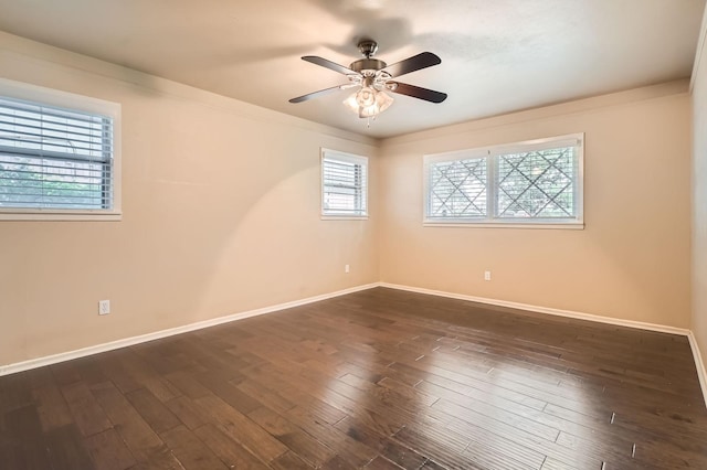 spare room with baseboards, a ceiling fan, and dark wood-type flooring