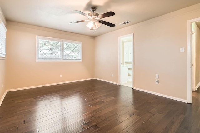empty room featuring ceiling fan, visible vents, dark wood-style floors, and baseboards