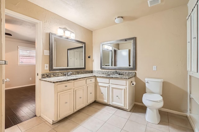 bathroom with a sink, toilet, double vanity, and visible vents