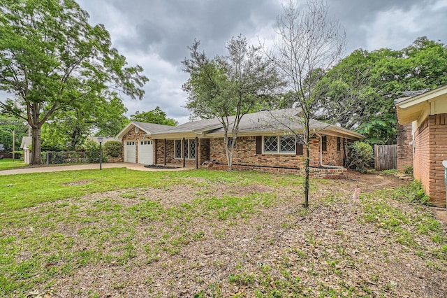 back of property with a garage, fence, brick siding, concrete driveway, and a yard