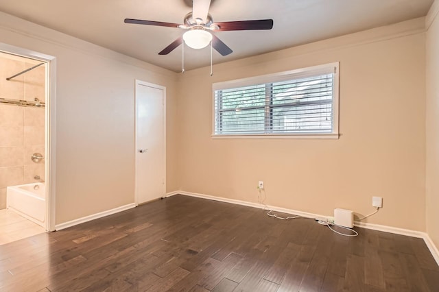 unfurnished bedroom featuring baseboards, a ceiling fan, ensuite bath, and wood finished floors
