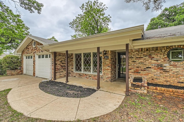 exterior space with a porch, an attached garage, driveway, and brick siding