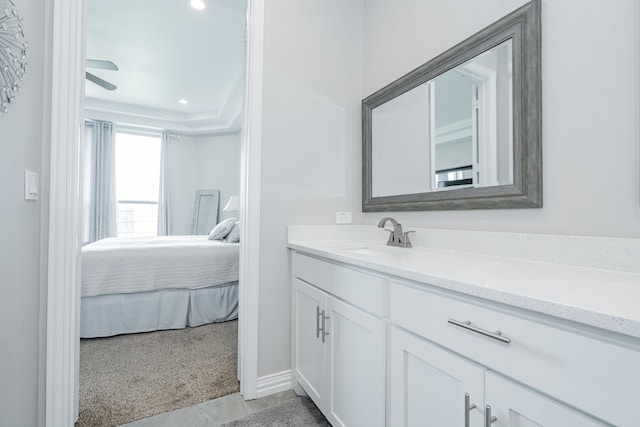 ensuite bathroom featuring vanity, baseboards, recessed lighting, connected bathroom, and a raised ceiling