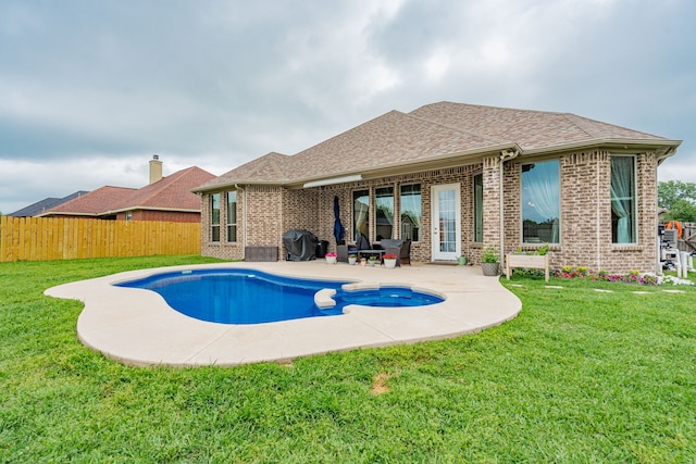 view of pool with a lawn, a patio, a pool with connected hot tub, and fence