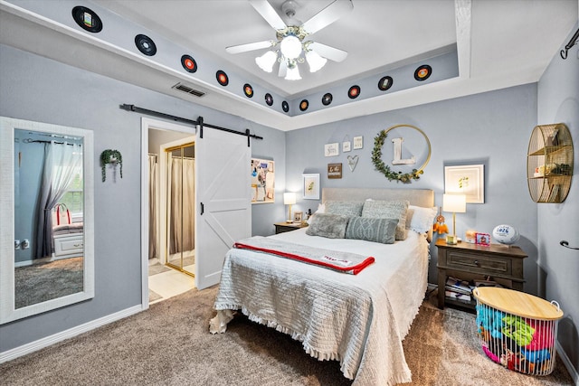 carpeted bedroom featuring a ceiling fan, baseboards, visible vents, and a barn door
