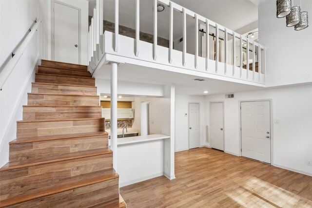 stairway featuring a high ceiling, visible vents, and wood finished floors
