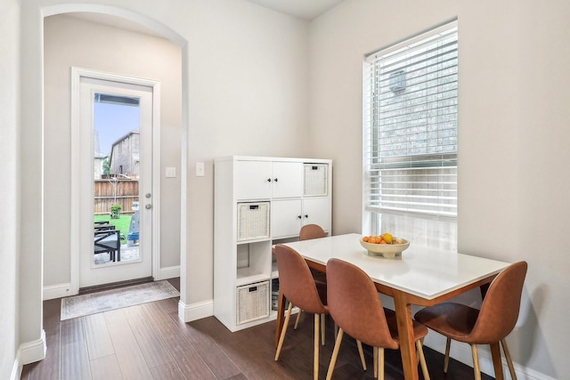 dining space featuring baseboards, dark wood finished floors, and a healthy amount of sunlight