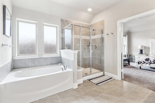ensuite bathroom with connected bathroom, a wealth of natural light, a garden tub, and a stall shower